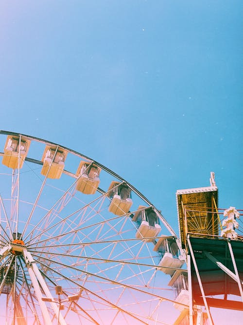 A ferris wheel is shown in a blue sky