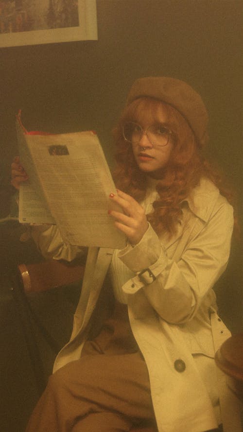 Woman Wearing Trench Coat and Reading a Newspaper 