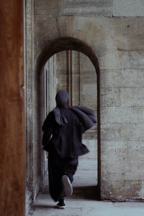 A person in a hoodie walking through an archway