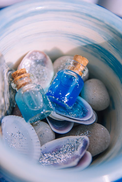 A blue and white bowl filled with seashells and small bottles