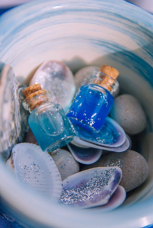 Blue and white seashells and a blue bottle with a blue liquid
