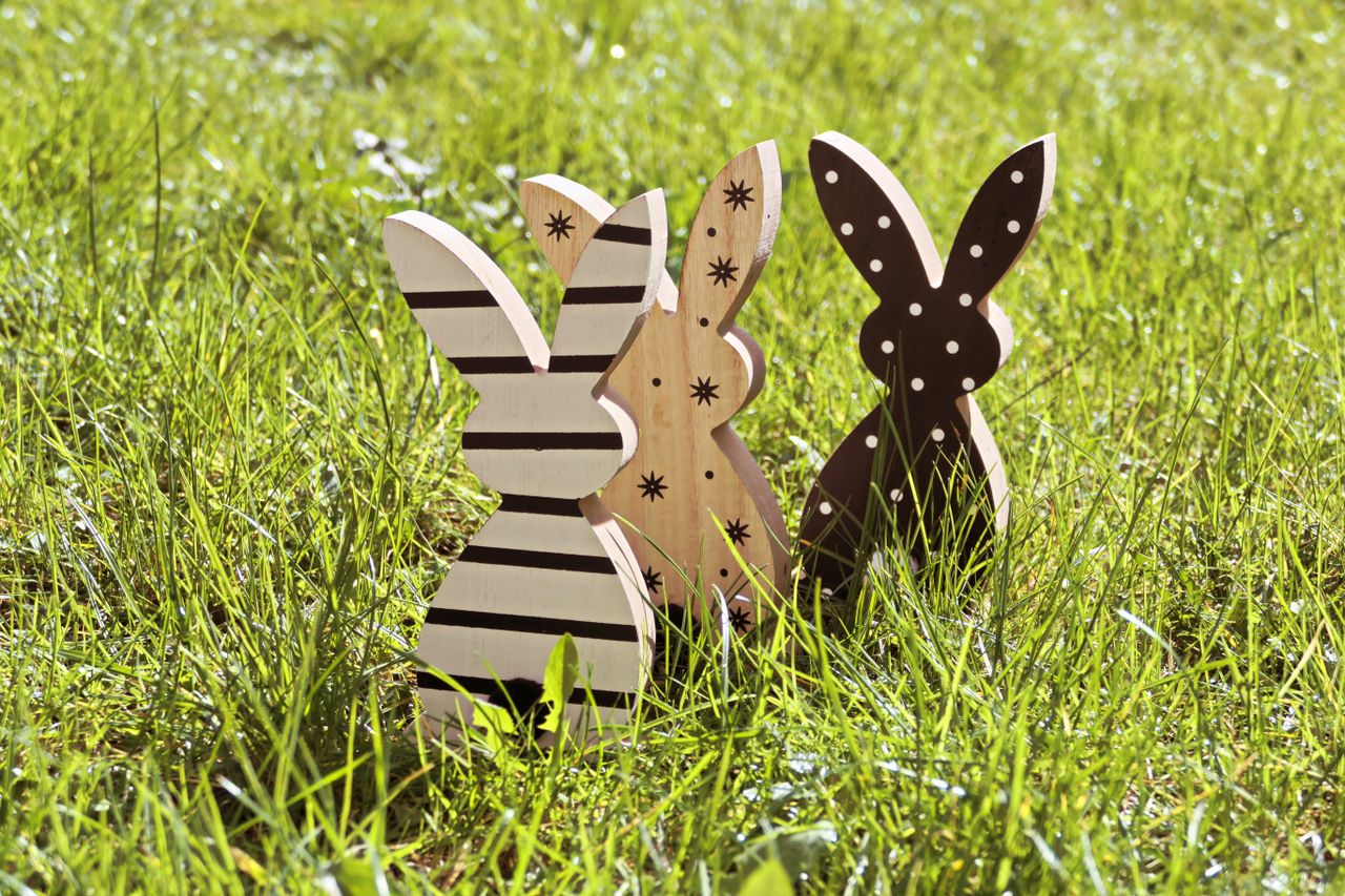 three wooden bunny decorations on green grass perfect for easter theme