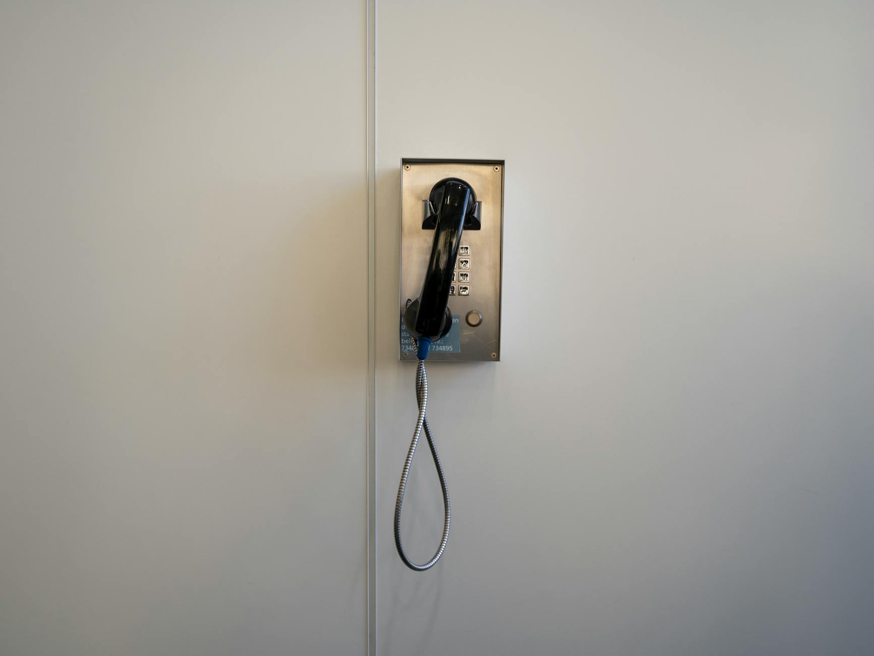 A vintage, wall-mounted payphone in a minimalist setting, showcasing retro technology.