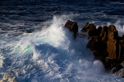 A large wave crashing into the rocks near the ocean