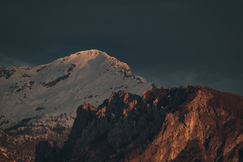 A mountain with a snow capped peak at sunset
