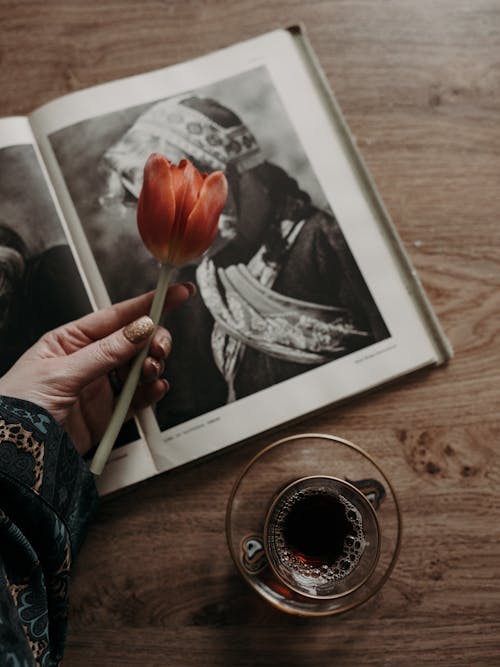 A person holding a tulip and a book