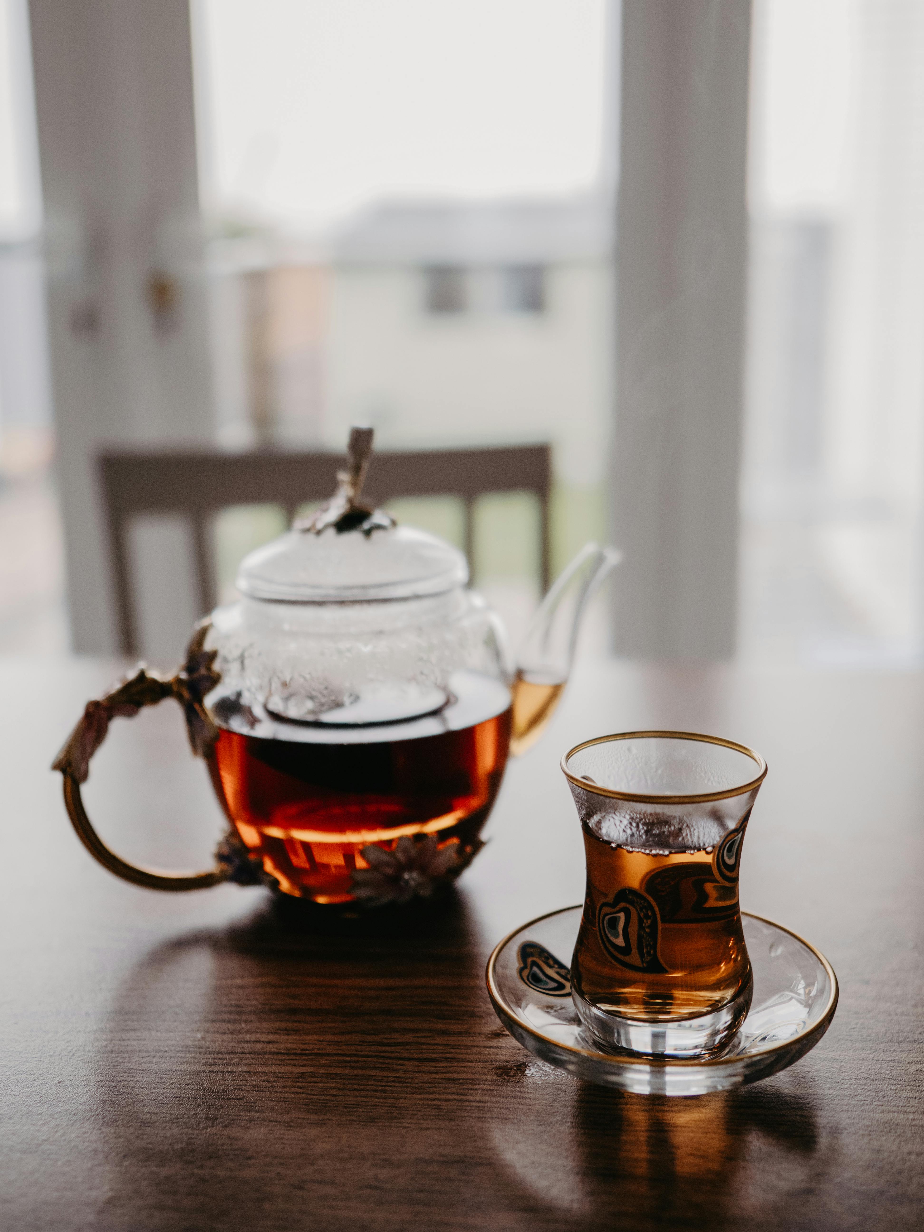 a glass teapot and a glass of tea standing on a table