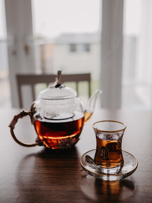A Glass Teapot and a Glass of Tea Standing on a Table 
