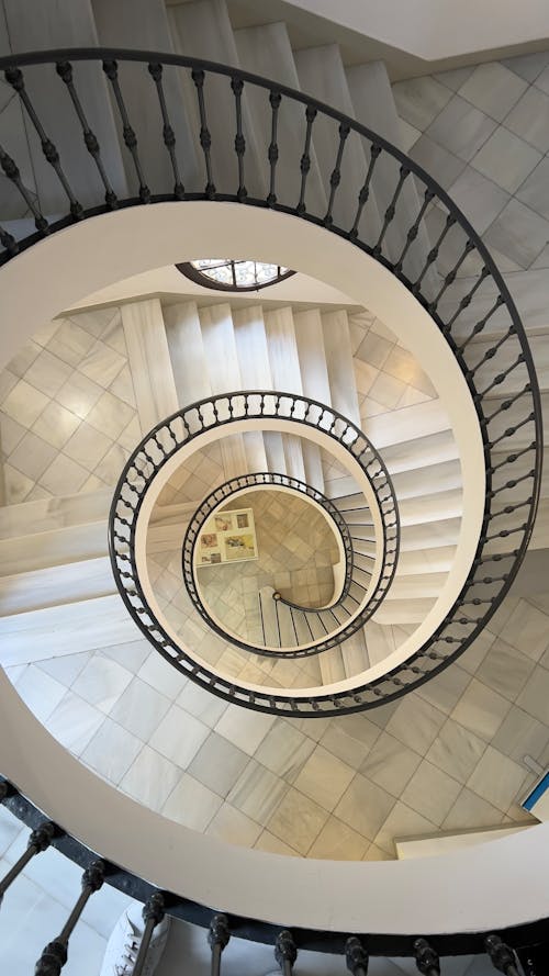 A spiral staircase with a marble floor and white walls