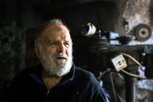 An older man with a beard and a black shirt