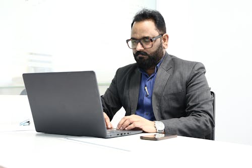 A man in a suit sitting at a desk with a laptop