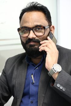 Businessman in gray suit and eyeglasses talking on phone.