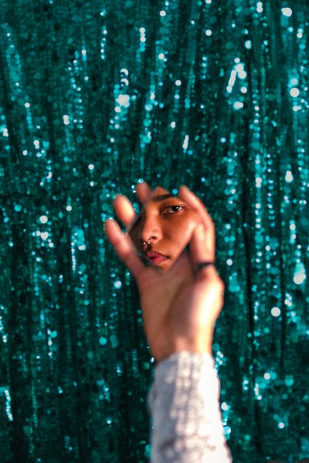 An artistic reflection in a mirror with a teal sequined background capturing a unique perspective.
