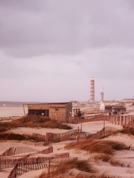 Scenic view of Aveiro lighthouse with sand dunes and coastal landscape at sunset in Aveiro, Portugal.