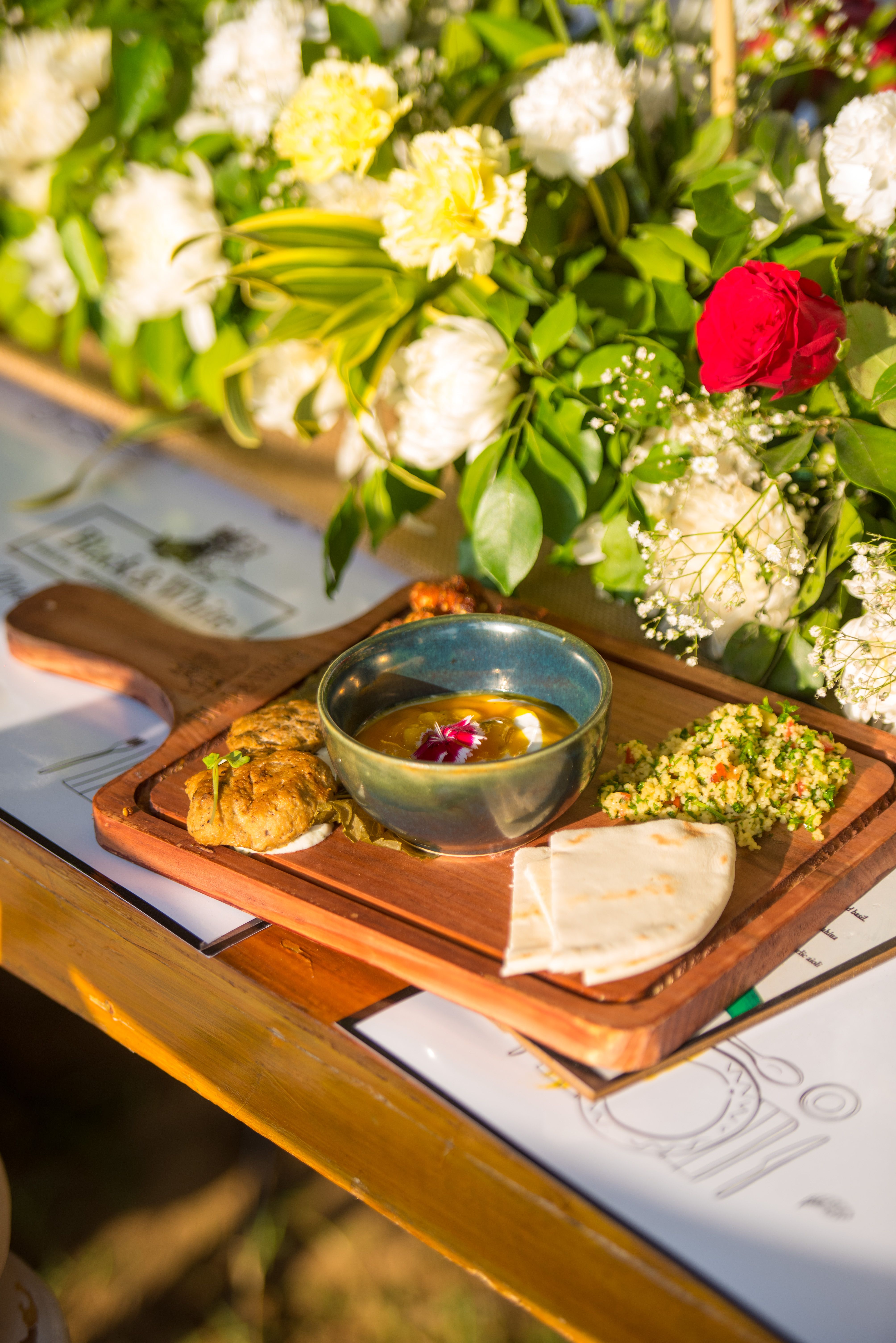 Mediterranean meal on a wooden board with vibrant flowers in New Delhi.