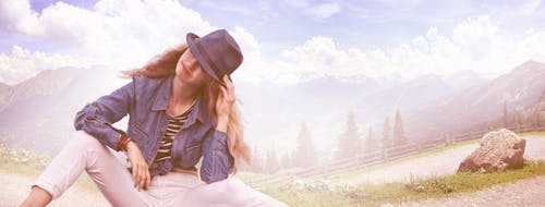 Free Woman Wearing Black Fedora Hat, Blue Denim Blazer and White Skinny Jeans While Sitting on Ground Stock Photo