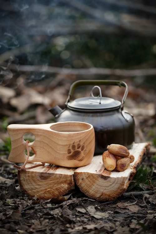 A wooden tea pot and a wooden spoon on a log