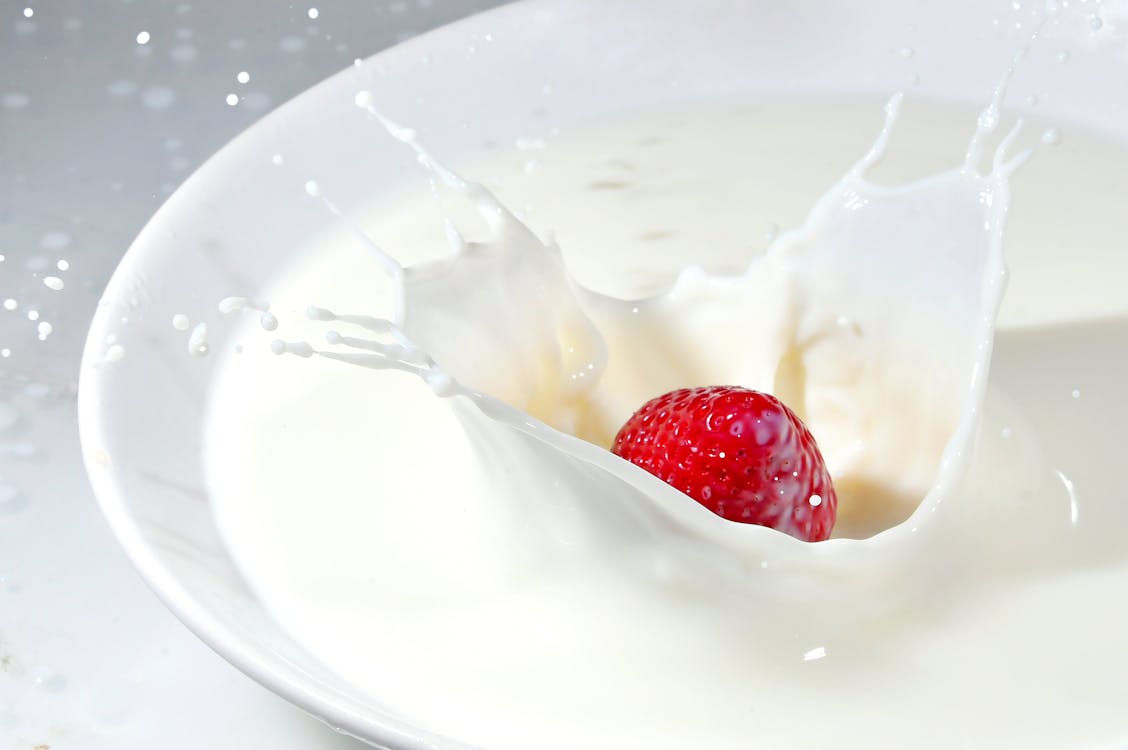 Free Time Lapse Photography of Strawberry Falling on Milk Stock Photo