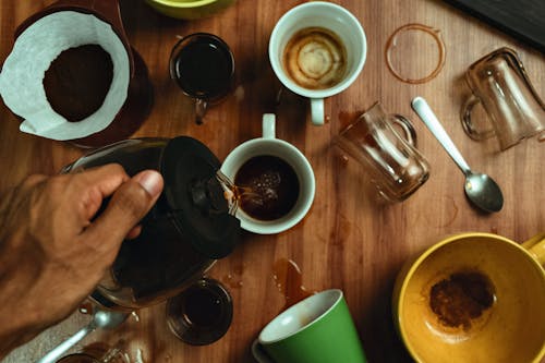 Man Hand Holding Pitcher over Mugs