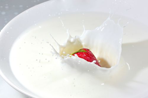 Free Detailed image of a strawberry splashing into fresh milk, creating a high-impact splash effect. Stock Photo