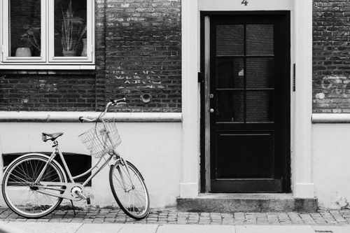 Free Black and white photo of a bicycle by a door in Copenhagen, Denmark. Stock Photo