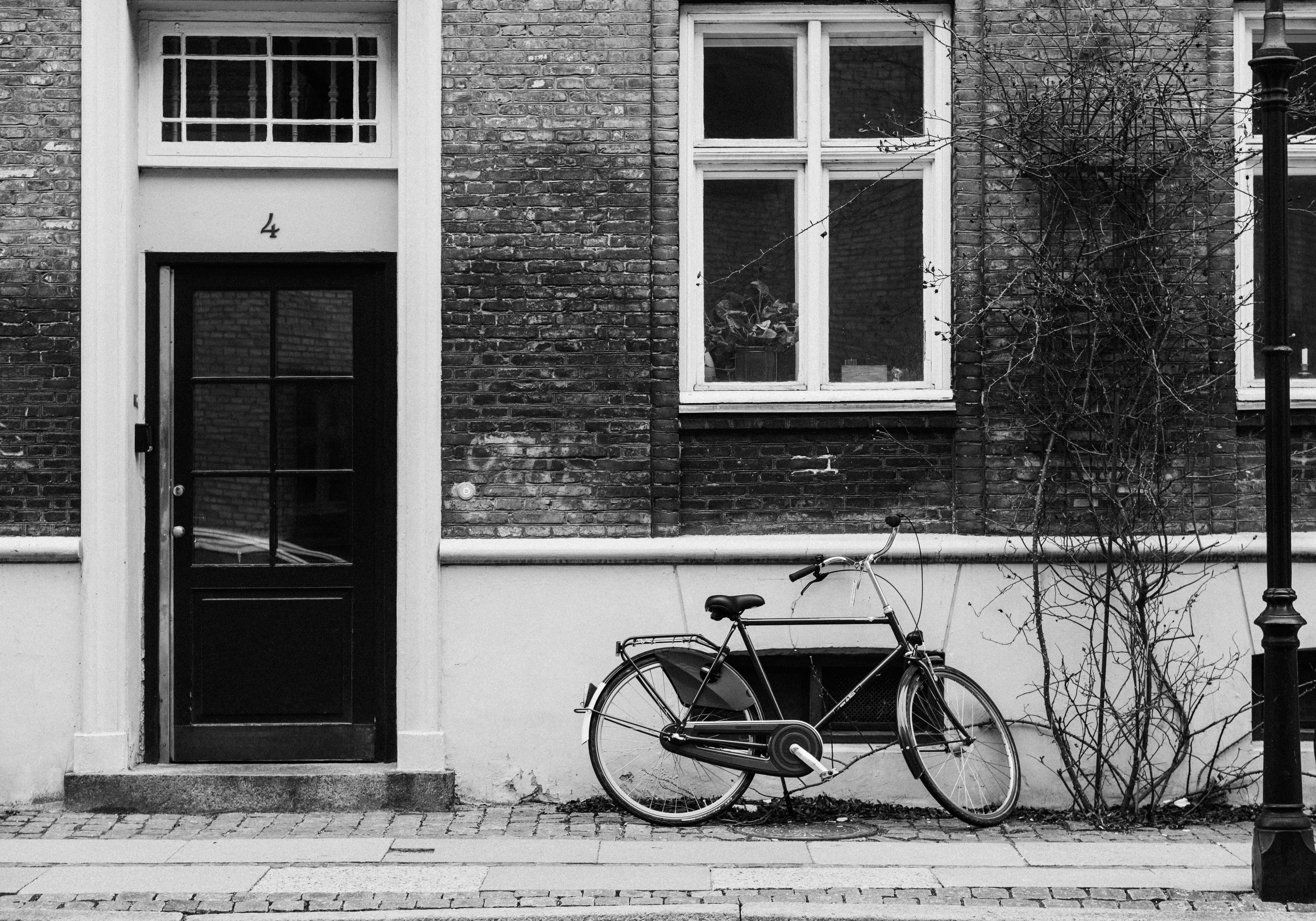 Black and white photo of a bicycle leaning against a brick building in Copenhagen.