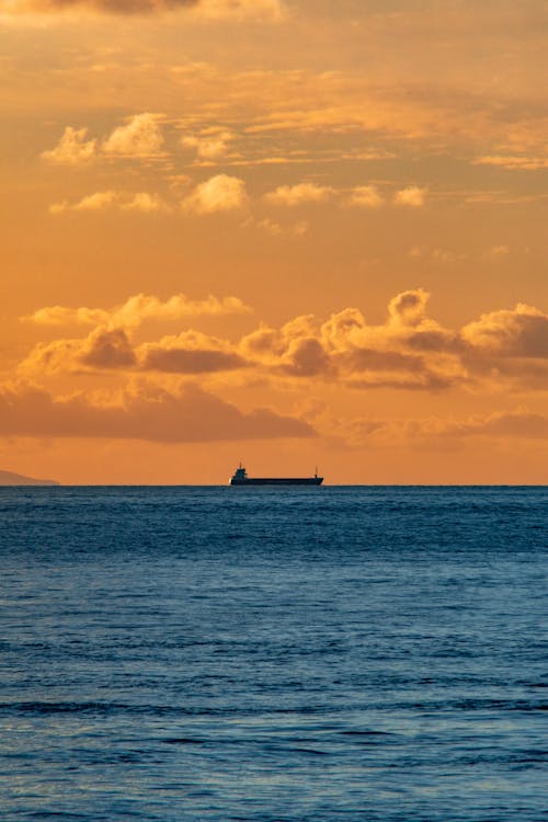 A boat is sailing in the ocean at sunset