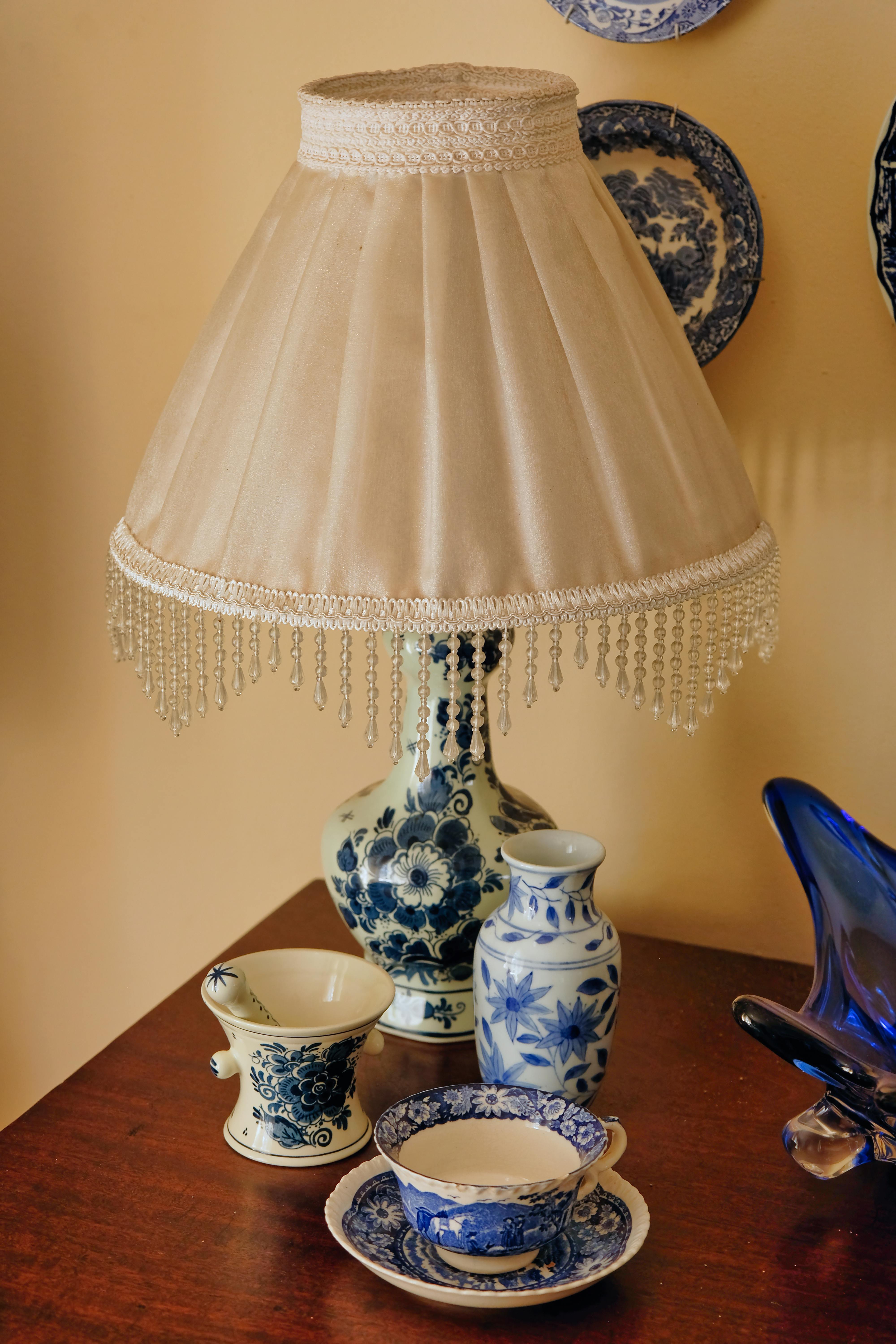 Beautiful display of blue and white ceramic pieces with a vintage lamp on a table.