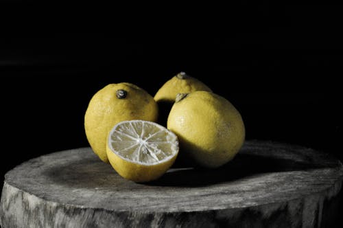 Три лимона рядом с нарезанным лимоном на дереве