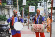 在城市街道的文化节游行中，两名身穿传统服装的男子正在打鼓