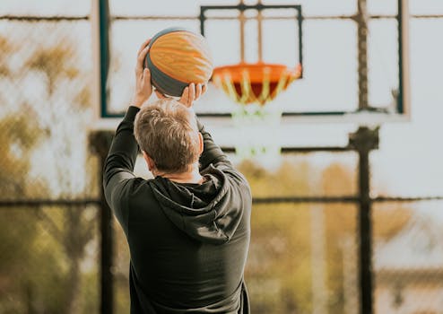 Adult man shooting basketball at a hoop outdoors in New York. Action and leisure captured.