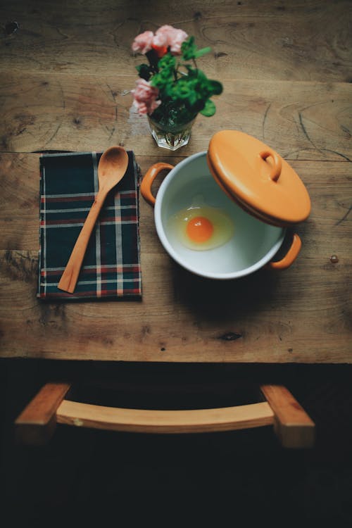 A wooden table with an egg and spoon on it