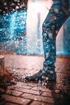A stylish individual walks through a rainy urban street, creating dynamic water splashes.