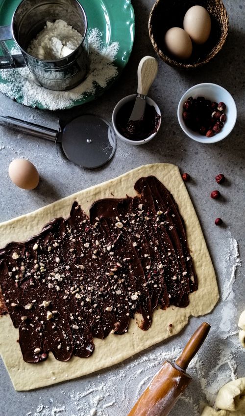 Free Overhead view of baking ingredients and tools showcasing chocolate spread on dough for pastry preparation. Stock Photo