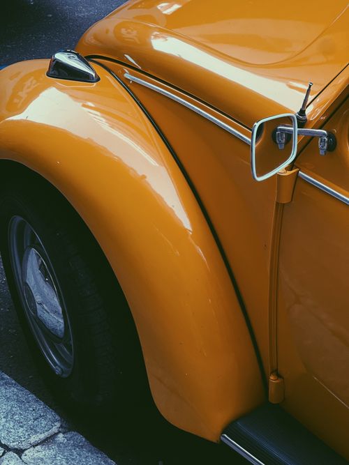 Free Detailed shot of a classic orange vintage car fender with retro design. Stock Photo