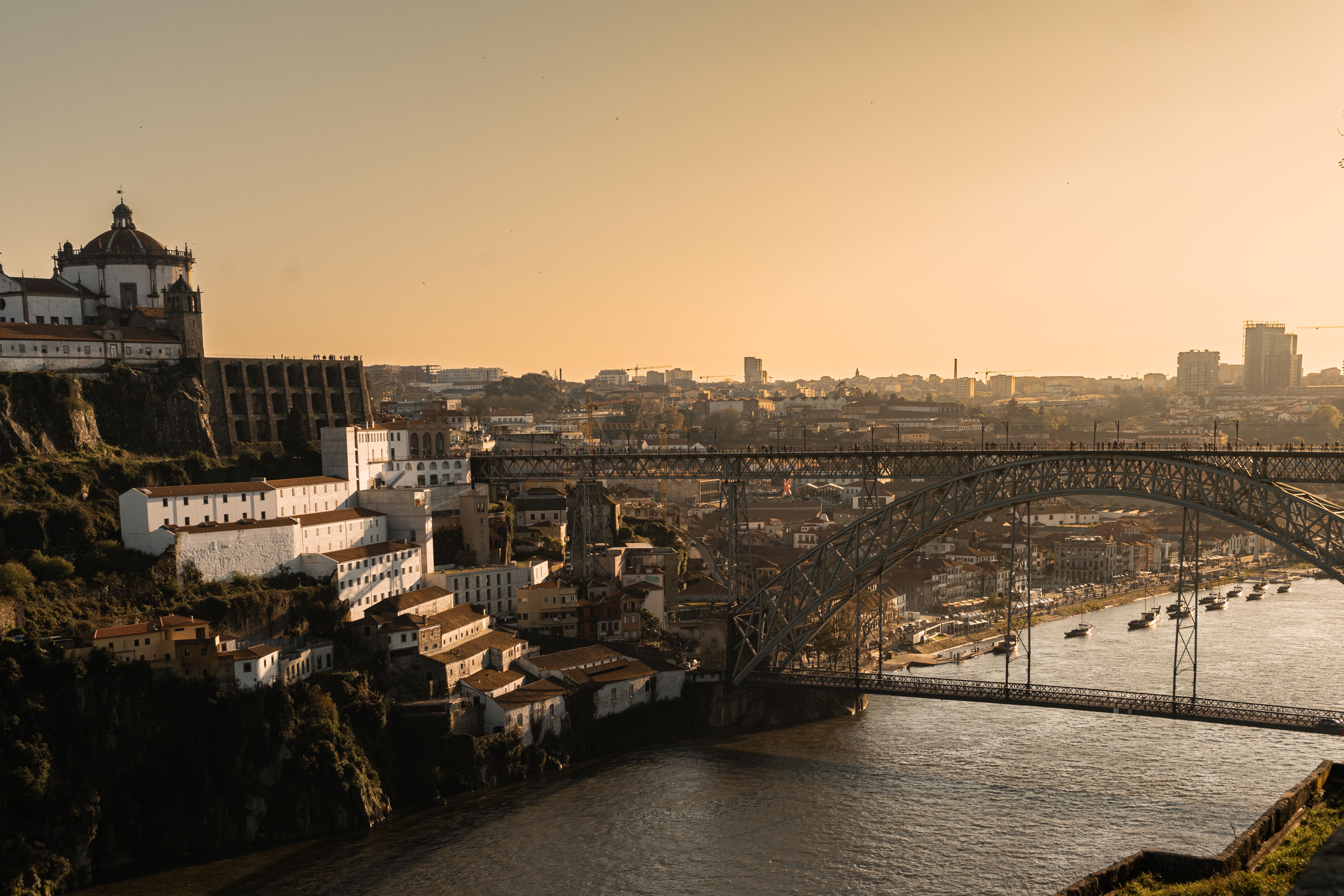 A captivating sunset view of Porto's skyline featuring the iconic Dom Luís I Bridge and riverfront.