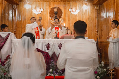 A priest and bride are standing in front of a wedding altar