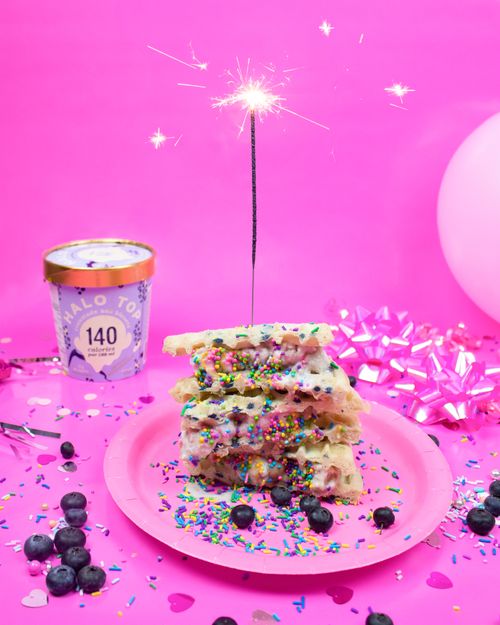 Free Colorful birthday treat with waffles, sprinkles, and a sparkler, set against a vibrant pink background. Stock Photo