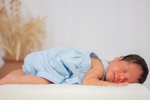 A serene image of a sleeping newborn baby in a blue outfit, conveying innocence and tranquility.