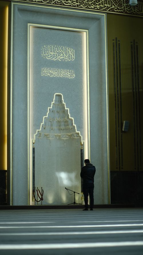 Free A man stands in quiet prayer inside a grand mosque, reflecting spirituality and solitude. Stock Photo