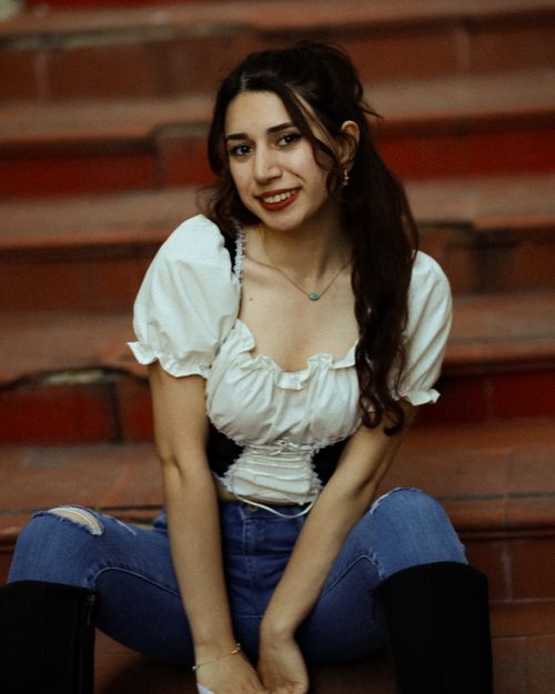 Free Young woman sitting on stairs, smiling in casual fashion attire. Stock Photo