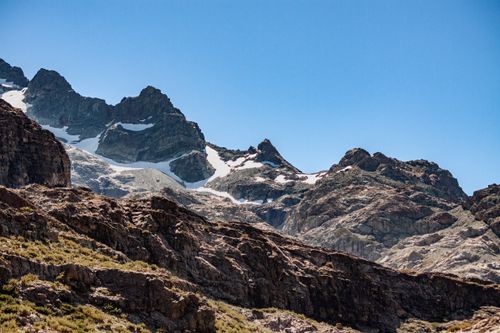 Free A stunning view of rugged mountain peaks with light snow under a clear blue sky, perfect for nature enthusiasts. Stock Photo