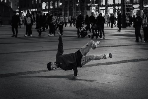 Free A breakdancer showcases moves in a bustling city square at night. Stock Photo
