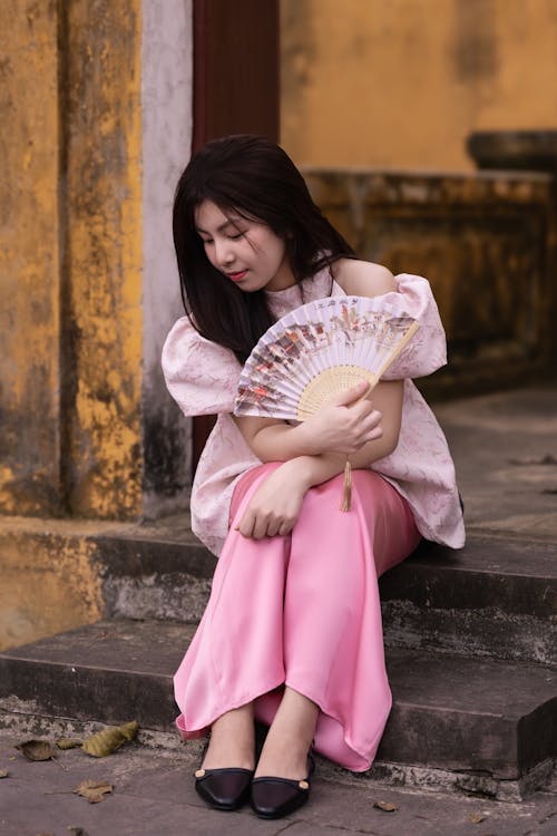 A woman sitting on the steps with a fan
