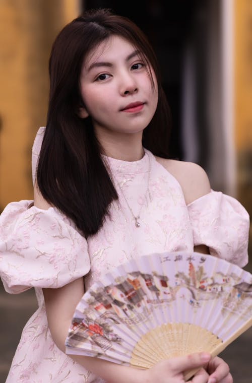 A woman in a pink dress holding a fan