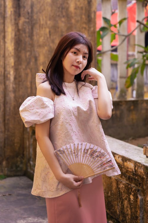 A woman in a pink dress holding a fan