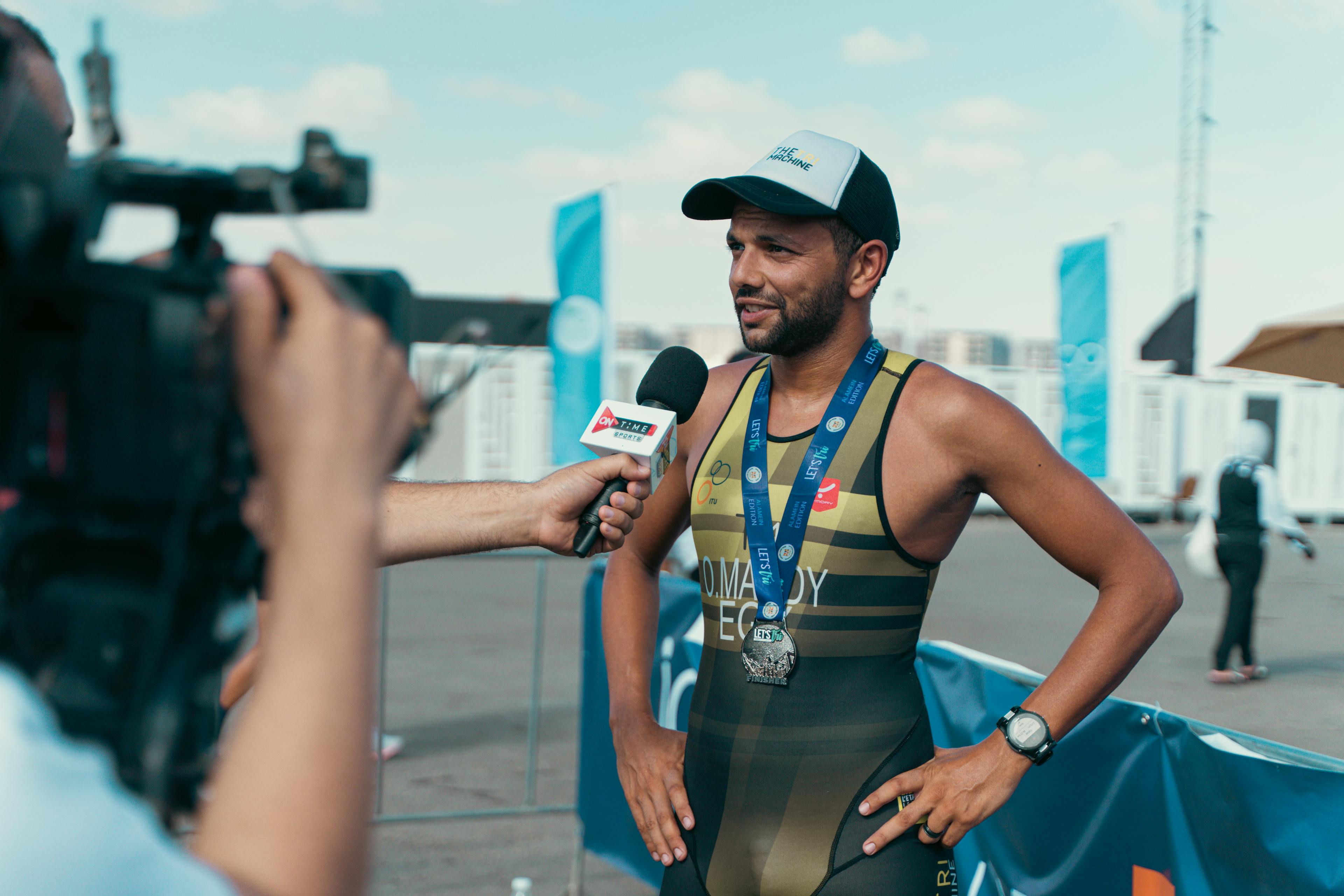 Triathlete interviewed after completing a race in Cairo, Egypt, wearing a medal and sportswear.