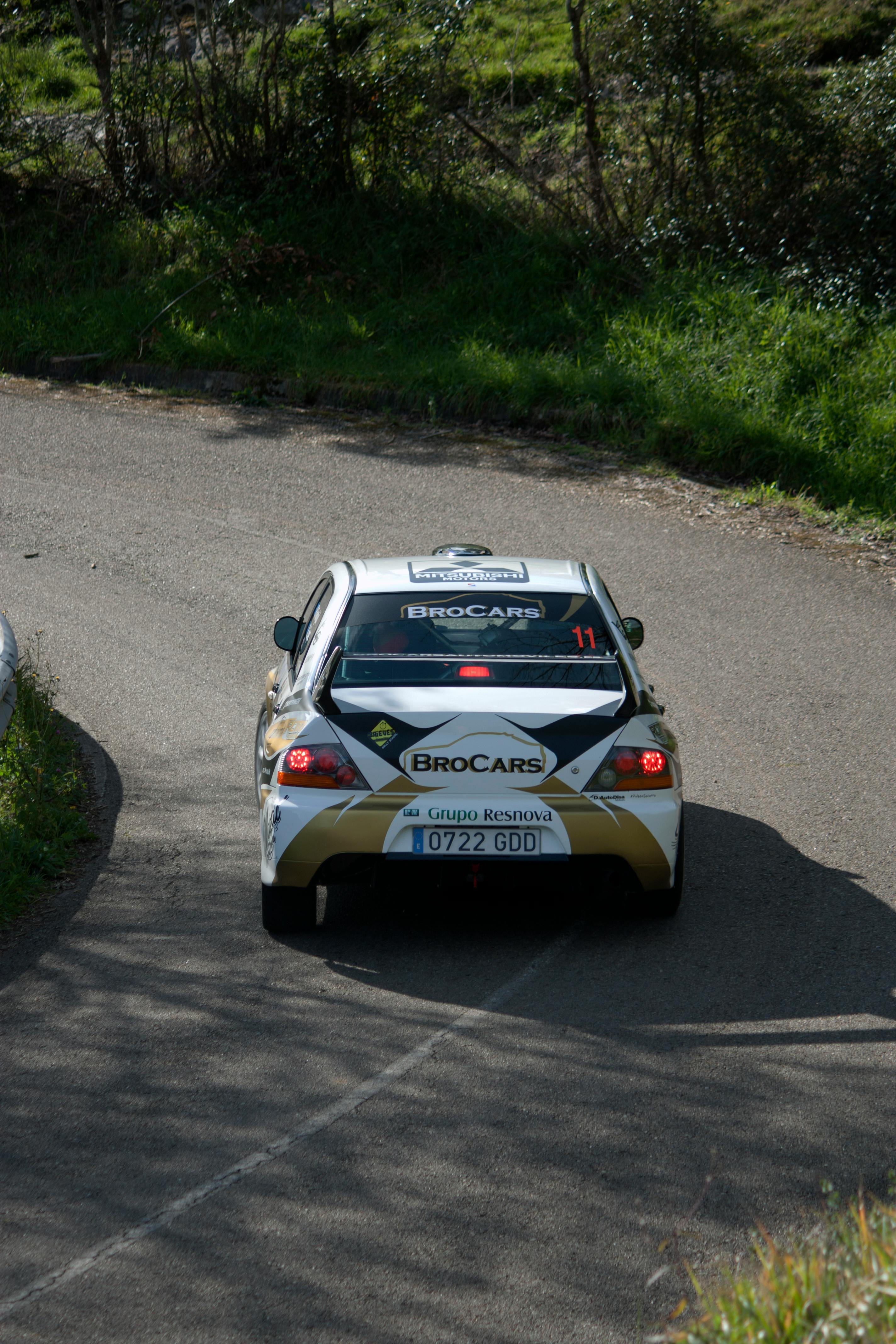 High-performance rally car taking a sharp turn on a scenic rural road.
