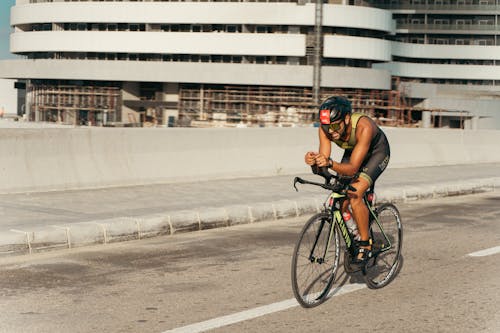 A man riding a bike on a road with a building in the background
