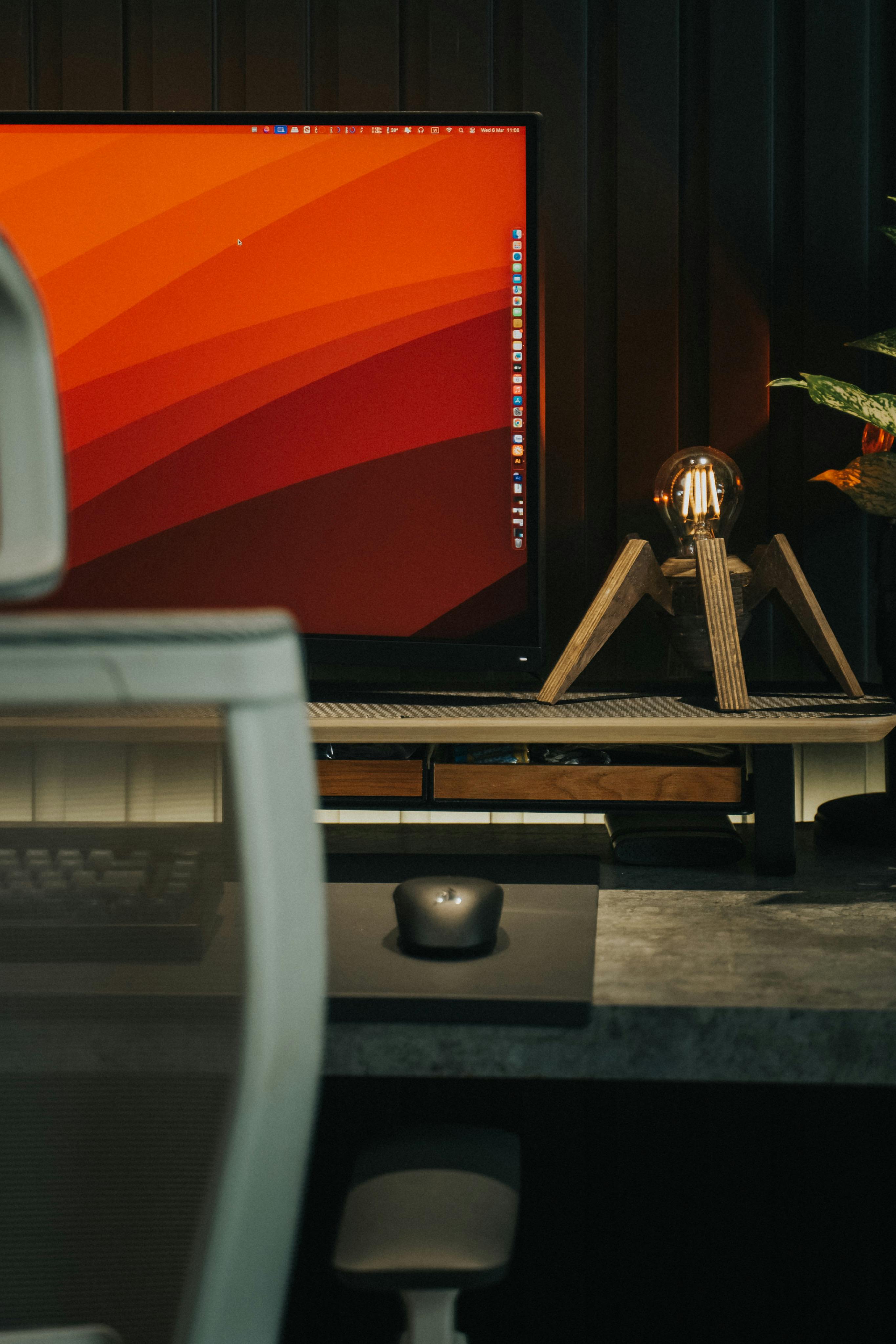 A minimalist workspace featuring a computer, mouse, and sleek lamp on a modern desk.